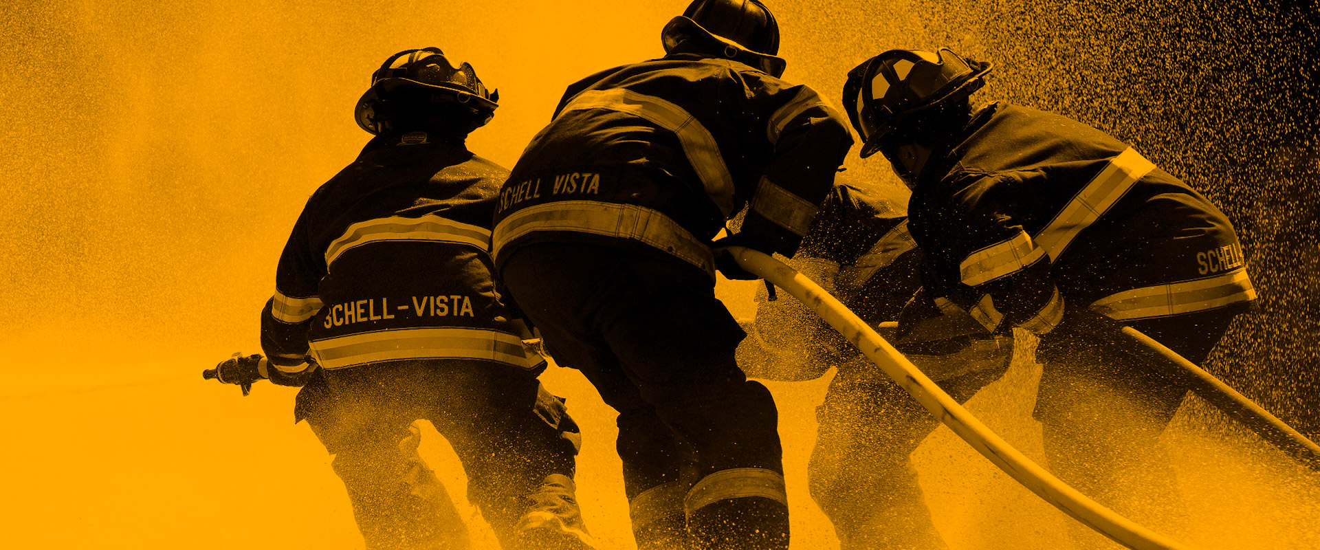 Tre brandmän i full utrustning sedda bakifrån, som hanterar en slang som sprutar vatten, med « SCHELL-VISTA » på jackorna.