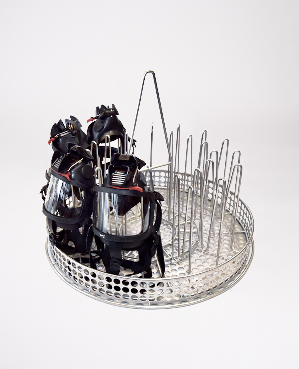 Gerätehalter mit Schutzmasken in einem runden, perforierten Korb mit Trennwänden zur Dekontamination.