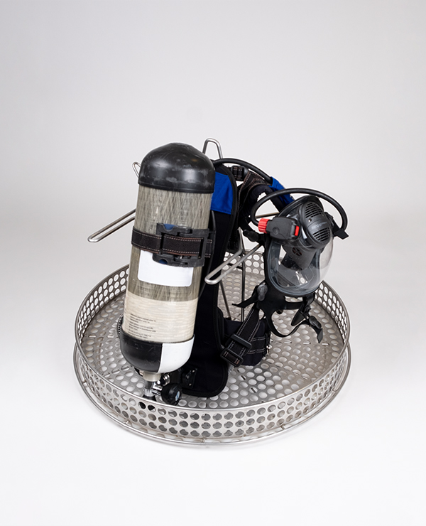 Atemschutzgerät (SCBA) mit Luftflasche und Vollmaske auf einem gelochten Metalltablett platziert.