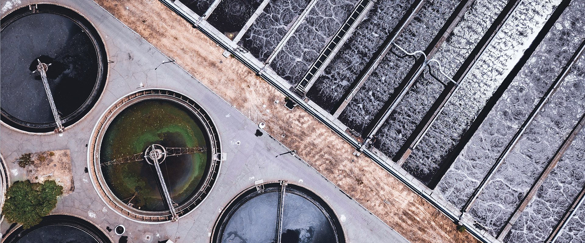 Aerial view of a wastewater treatment plant with circular and rectangular tanks for water purification.