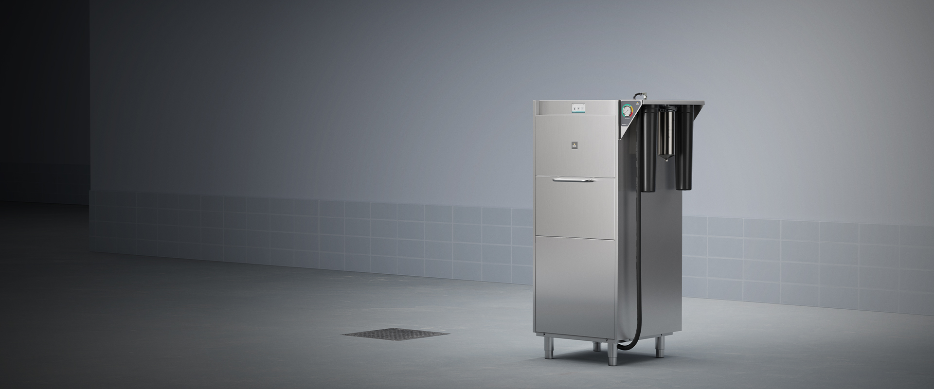 Metallic gear washer in tiled room with three cylindrical filters on right side and control panel on front.