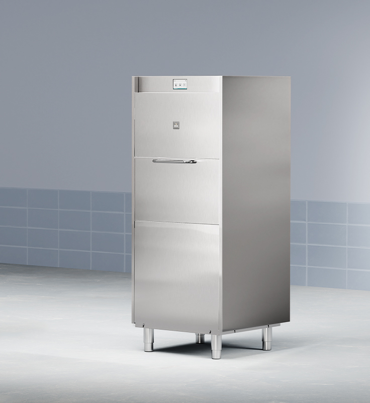 Stainless steel cleaning machine for firefighter gear, with control panel and handle, on tiled floor against blue tiled wall.