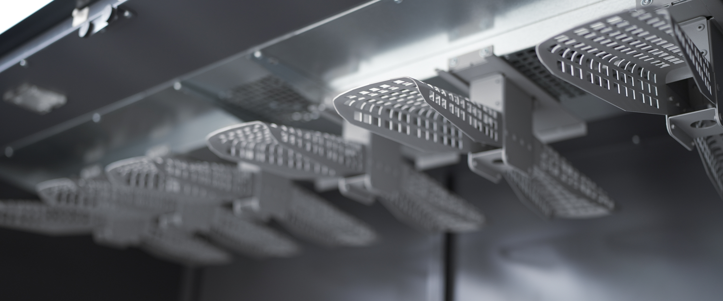 Close-up of metal hangers with perforated surfaces inside a drying cabinet, designed for air circulation.