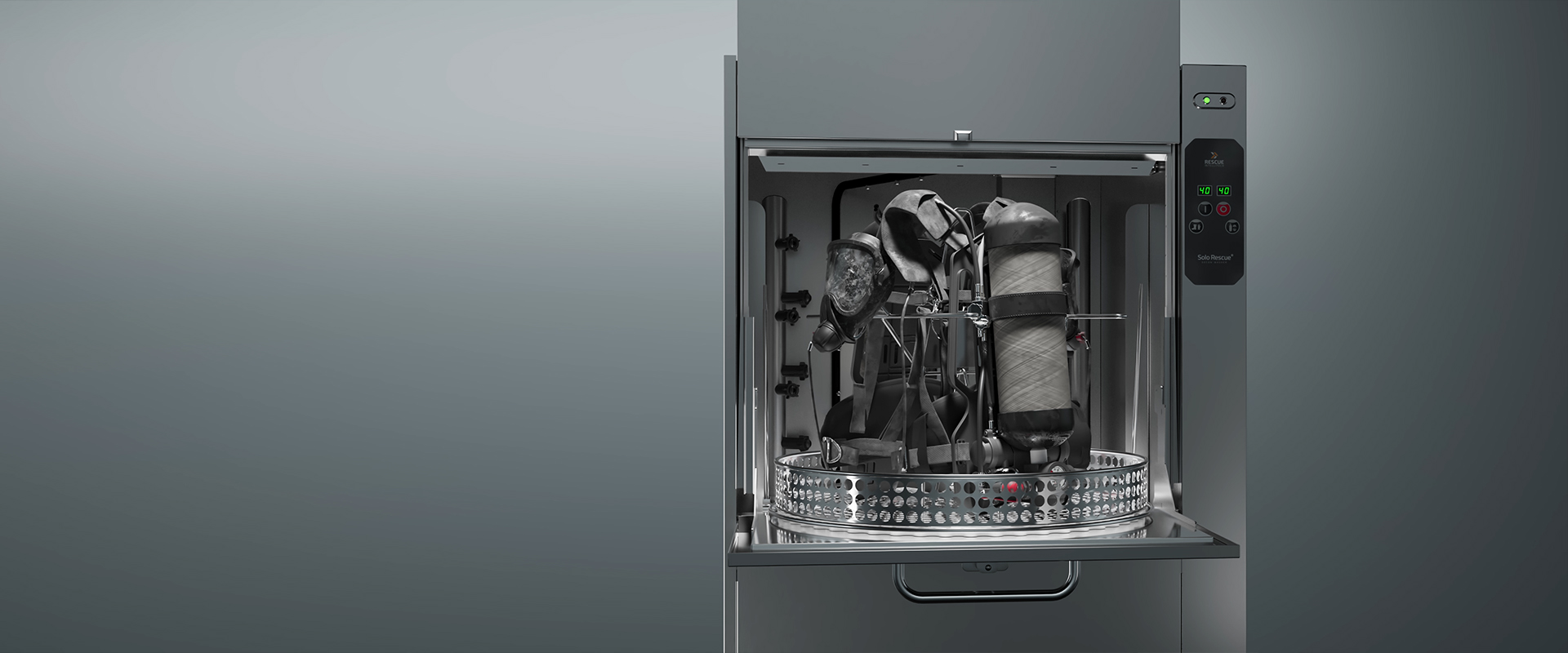 Open industrial washing machine with firefighter gear inside, including a breathing apparatus; control panel on the right side.